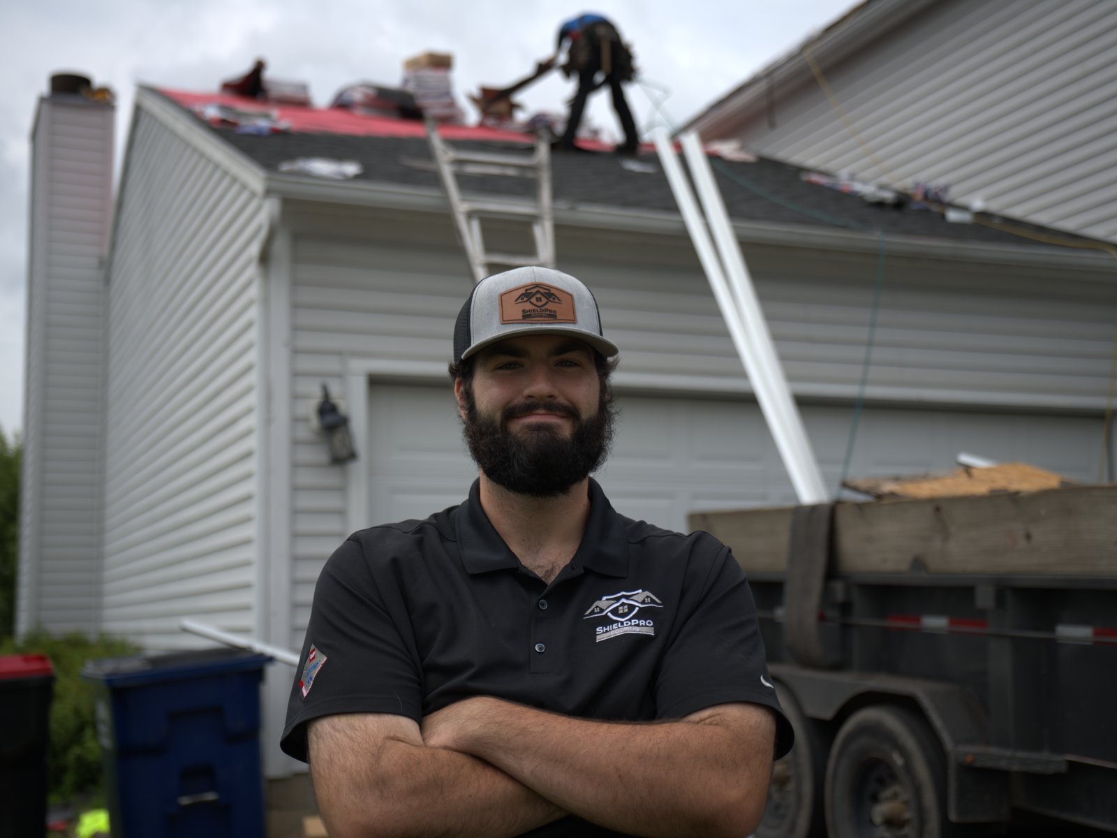 ShieldPro Roofing crew member standing in front of a roof tear-off